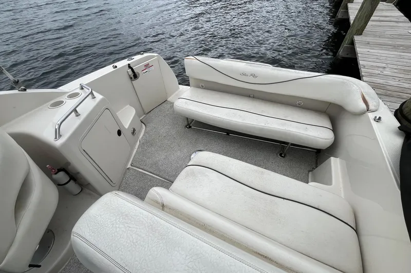 Slide: The Image of 2004 Sea Ray 240 Sundancer boat interior with white seating and dockside view. - 34