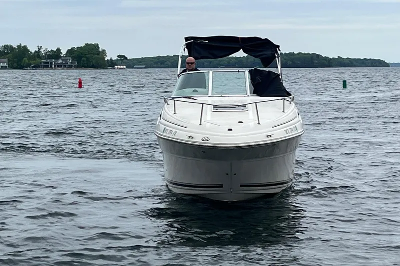 Slide: The Image of 2004 Sea Ray 240 Sundancer cruising on a lake with scenic shoreline. - 4