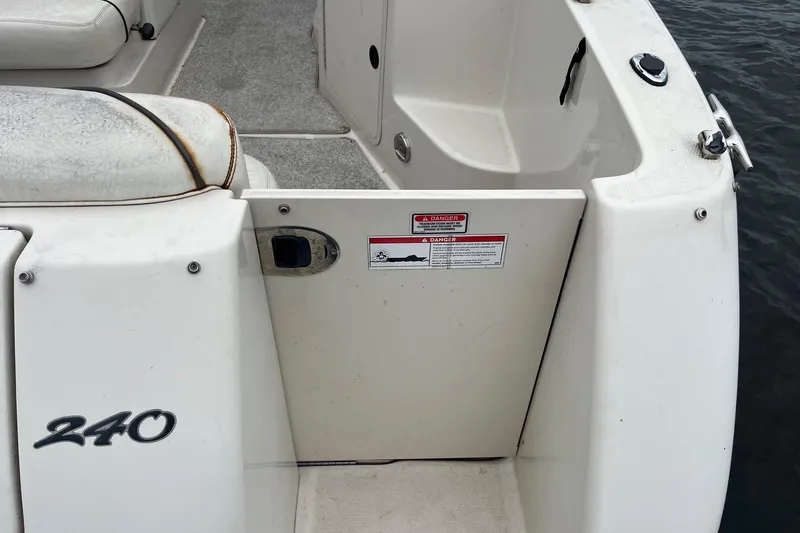 Slide: The Image of 2004 Sea Ray 240 Sundancer boat interior with seating and safety warning label. - 8