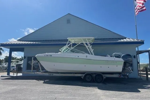 The Image of 2024 World Cat 230 SD boat on trailer outside a building with American flag. - 1