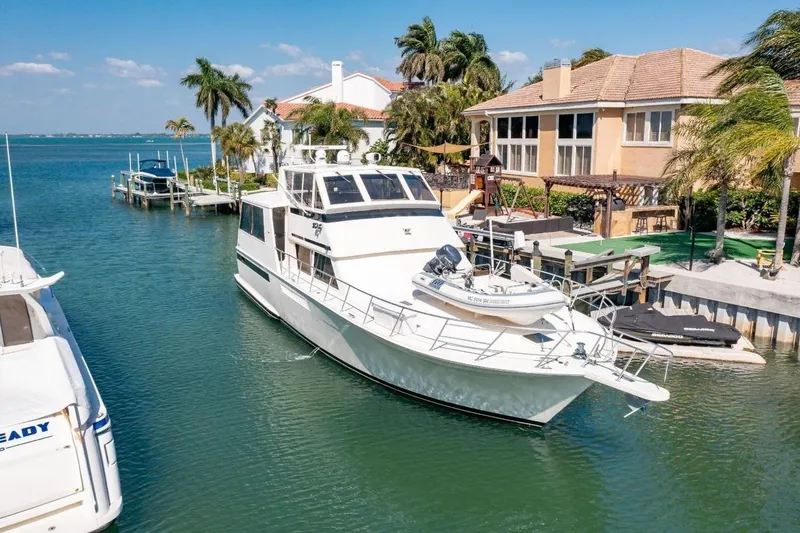 The Image of 1993 Viking Convertible yacht docked near waterfront homes, surrounded by palm trees and clear blue water. - 1