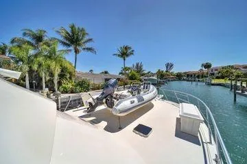 Slide: The Image of 1993 Viking Convertible yacht with dinghy on deck, docked near palm trees and canal. - 19