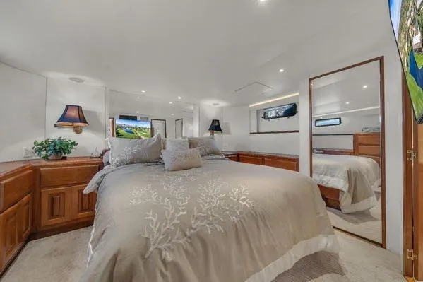 Slide: The Image of Luxurious bedroom interior in a 1993 Viking Convertible yacht, featuring elegant bedding and wooden cabinetry. - 30