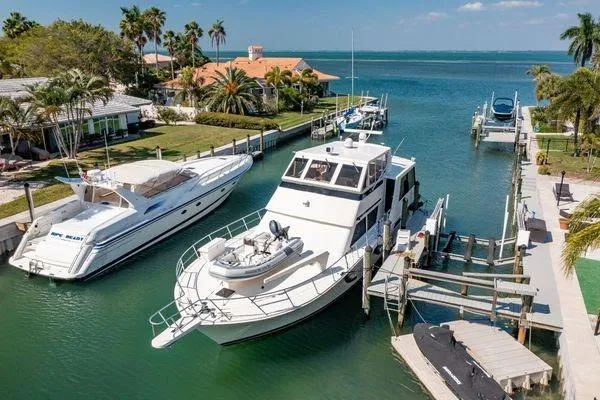 The Image of 1993 Viking Convertible yacht docked in a scenic marina with palm trees and waterfront homes. - 4