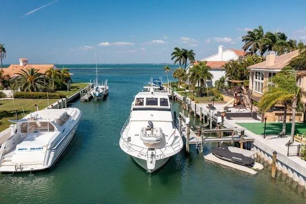 Slide: The Image of 1993 Viking Convertible yacht docked in a scenic waterfront marina with palm trees. - 5