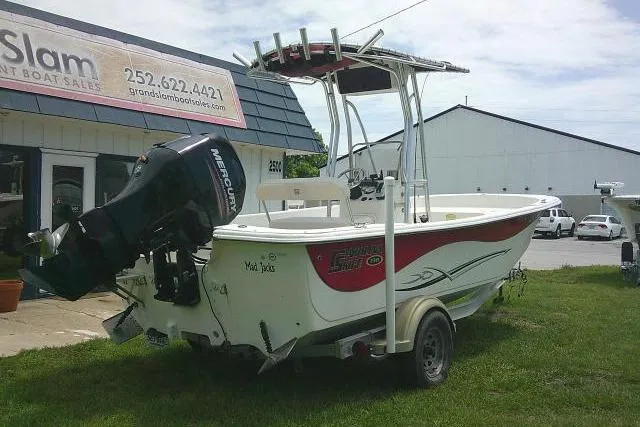 Slide: The Image of 2013 Carolina Skiff 198 DLV boat with outboard motor on trailer, parked outside dealership. - 2