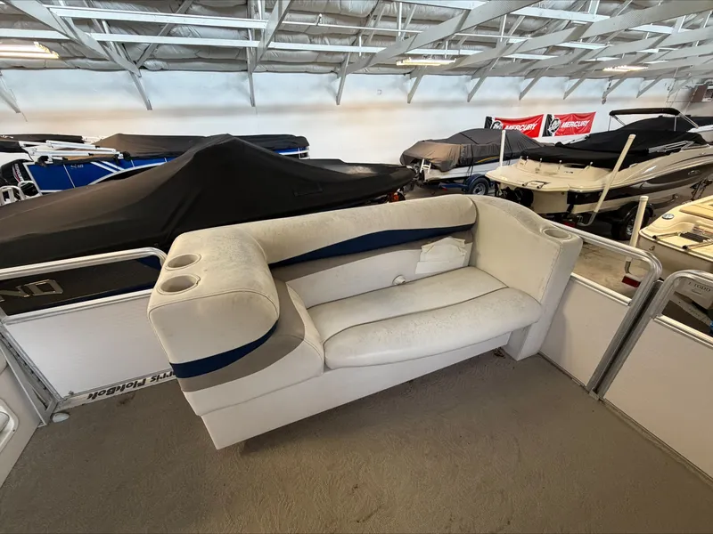 Slide: The Image of A white sofa with blue accents on a boat, surrounded by other covered boats in a warehouse. - 20
