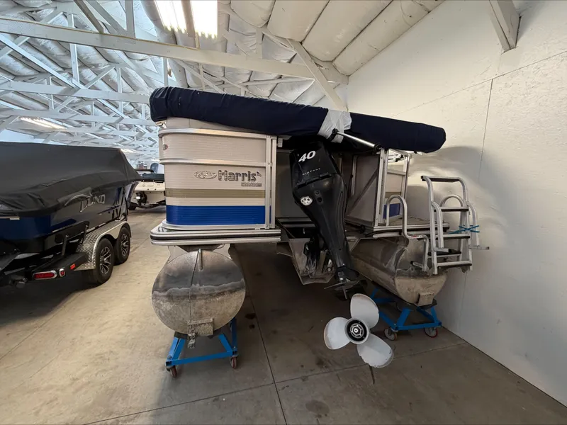 Slide: The Image of A 2007 Harris Sunliner 180 pontoon boat is in a warehouse. It features an outboard motor. - 2