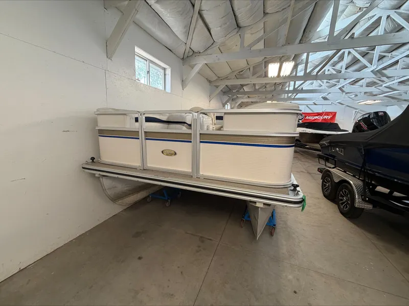 Slide: The Image of A 2007 Harris Sunliner 180 pontoon boat is indoors on blue stands. - 1
