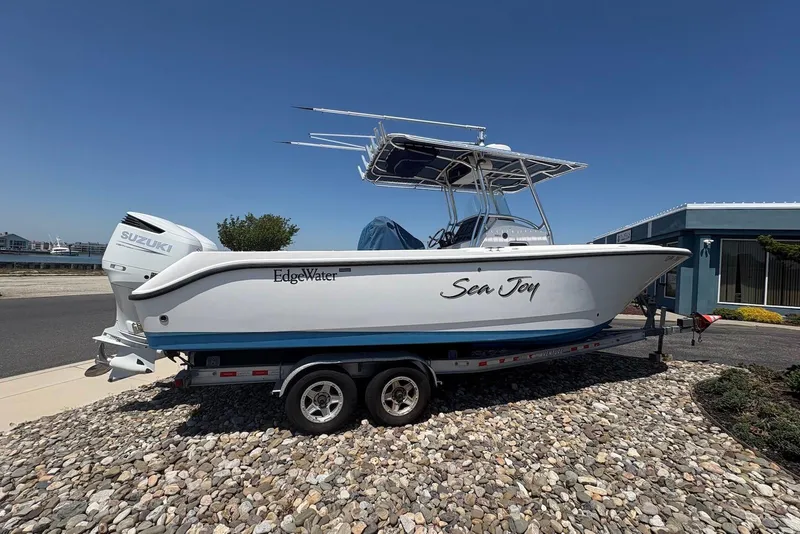 The Image of 2008 Edgewater 268CC boat named "Sea Joy" on a trailer, parked outdoors. - 2