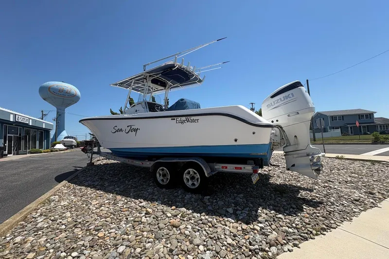 Slide: The Image of 2008 Edgewater 268CC boat on trailer with Suzuki engine, parked on rocky surface. - 4