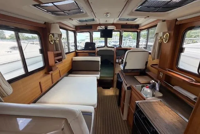 Slide: The Image of Interior of a 2016 Ranger Tugs R-27 boat, featuring cozy seating and wooden finishes. - 12