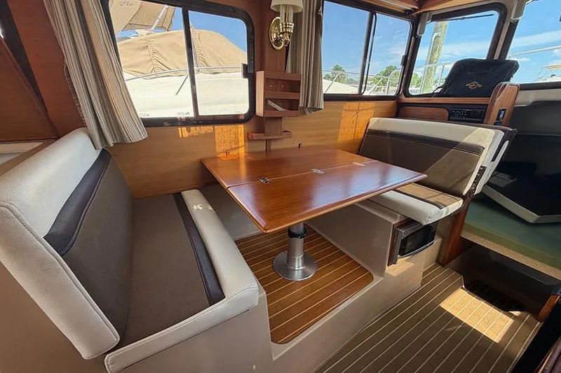 Slide: The Image of Interior of 2016 Ranger Tugs R-27 boat with wooden table and seating area. - 16