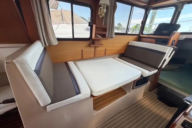Slide: The Image of 2016 Ranger Tugs R-27 interior with convertible seating and wood accents. - 18