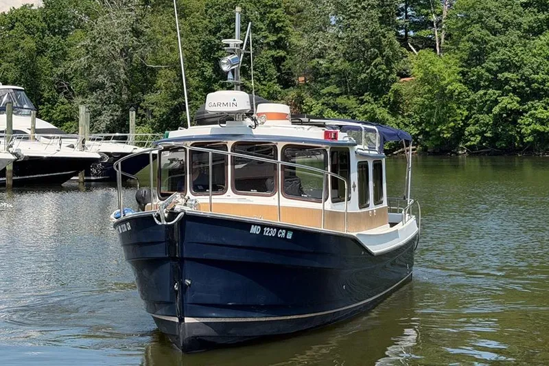 Slide: The Image of 2016 Ranger Tugs R-27 boat on a calm river with lush green trees. - 2
