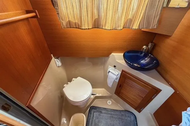 Slide: The Image of 2016 Ranger Tugs R-27 boat bathroom with toilet, sink, and wooden cabinetry. - 20