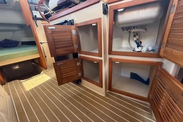 Slide: The Image of 2016 Ranger Tugs R-27 interior with open wooden cabinets and striped flooring. - 22