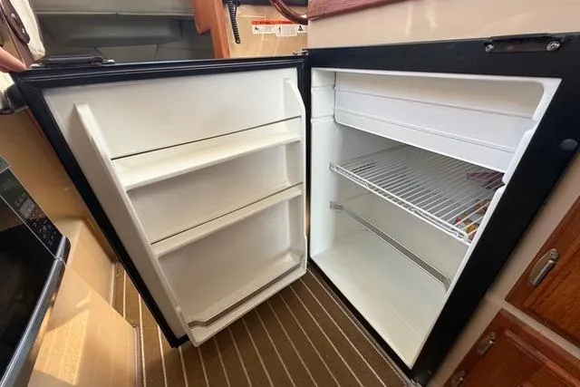 Slide: The Image of Open refrigerator inside 2016 Ranger Tugs R-27 boat, showing shelves and storage space. - 24