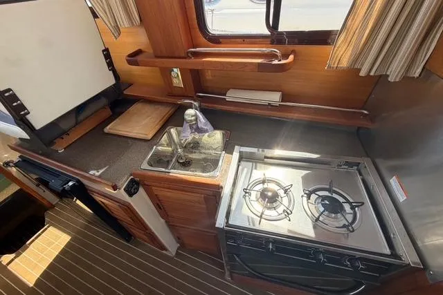 Slide: The Image of Compact kitchen area in a 2016 Ranger Tugs R-27 boat with stove and sink. - 25