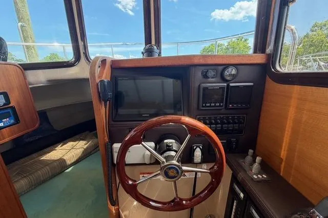 Slide: The Image of 2016 Ranger Tugs R-27 helm with wooden steering wheel and navigation controls. - 27