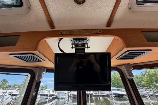 Slide: The Image of Interior view of a 2016 Ranger Tugs R-27 boat with mounted TV and marina background. - 29