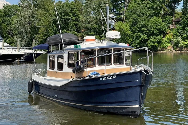 Slide: The Image of 2016 Ranger Tugs R-27 boat on a calm lake with lush greenery. - 3