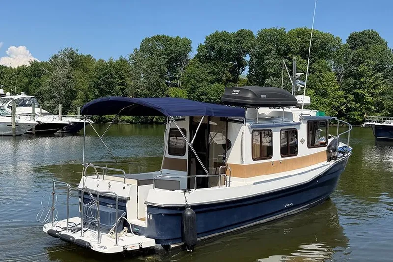 Slide: The Image of 2016 Ranger Tugs R-27 boat docked on a serene lake with lush greenery. - 4