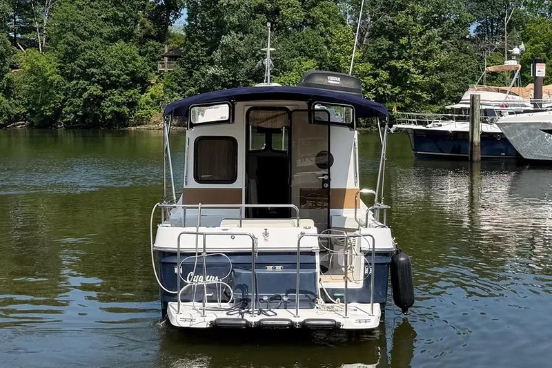 Slide: The Image of 2016 Ranger Tugs R-27 boat docked on a calm river with lush greenery. - 5