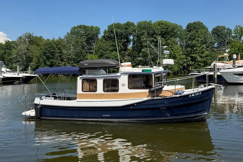 Slide: The Image of 2016 Ranger Tugs R-27 boat on calm water, surrounded by lush greenery. - 6