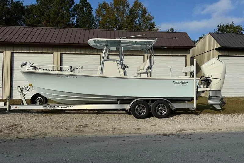 The Image of 2023 Pair Customs 24 Center Console DV boat on trailer, parked outside storage units. - 1