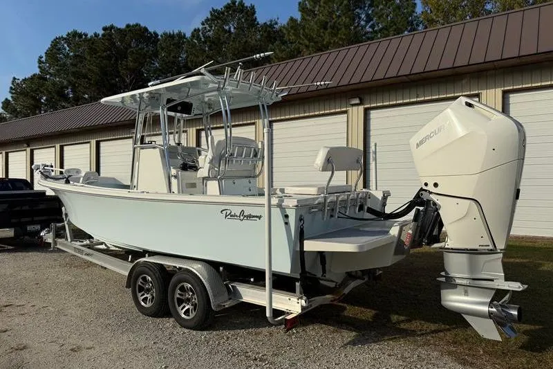 Slide: The Image of 2023 Pair Customs 24 Center Console DV boat on trailer, parked near storage units. - 2