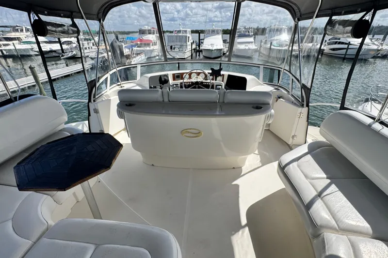 The Image of 2003 Silverton 43 Motor Yacht interior with helm, seating, and marina view. - 11