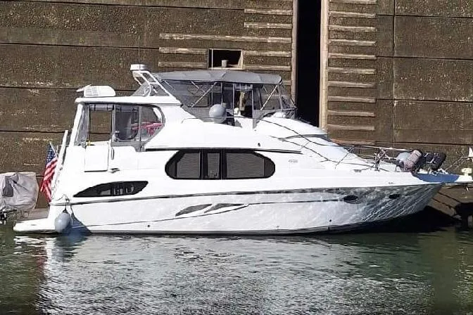 Slide: The Image of 2003 Silverton 43 Motor Yacht docked, featuring sleek design and American flag. - 2