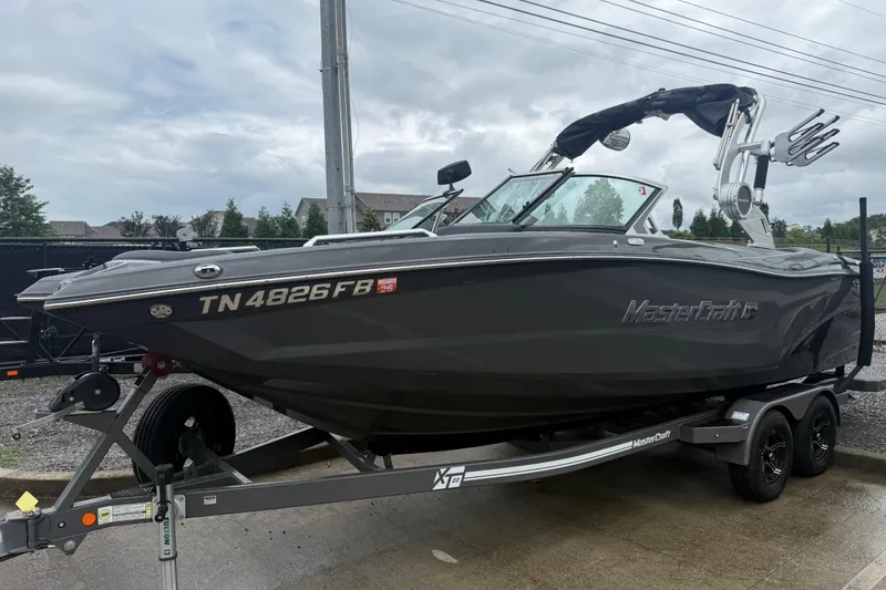 The Image of 2021 MasterCraft XT22 boat on trailer, sleek design, gray color, parked outdoors. - 0