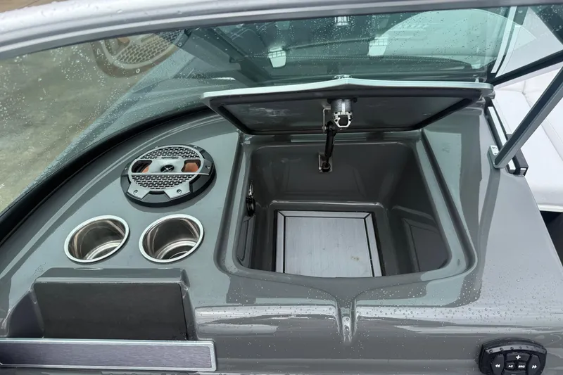 Slide: The Image of 2021 MasterCraft XT22 boat interior with open storage compartment and cup holders. - 22