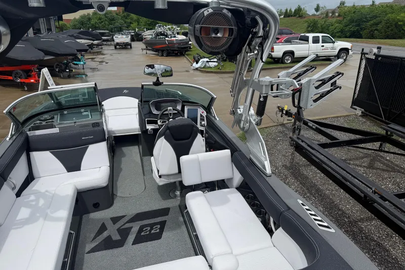 Slide: The Image of 2021 MasterCraft XT22 boat interior with seating and control panel, parked outdoors. - 33