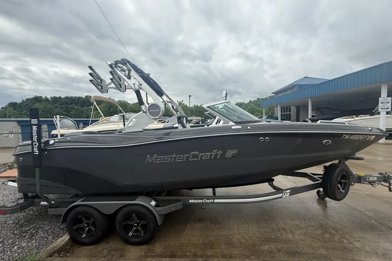 Slide: The Image of 2021 MasterCraft XT22 boat on trailer, parked outdoors under cloudy sky. - 5