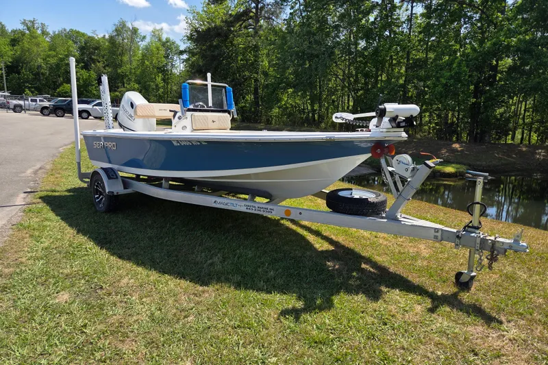 The Image of 2024 Sea Pro 172 Bay boat on trailer, parked on grass near a pond. - 1