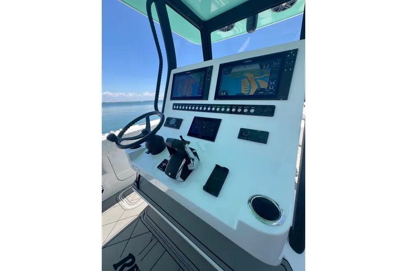 Slide: The Image of Control panel of 2026 Reef Runner 340 boat with navigation screens and steering wheel. - 12