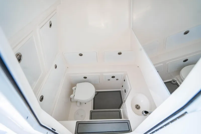 Slide: The Image of 2026 Reef Runner 340 boat interior with compact bathroom, featuring a toilet and sink. - 19