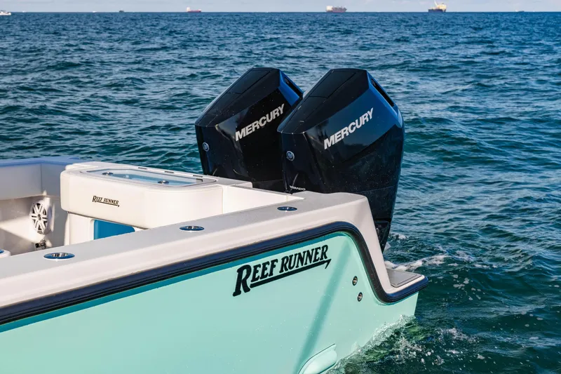 Slide: The Image of 2026 Reef Runner 340 boat with dual Mercury engines on open water. - 2