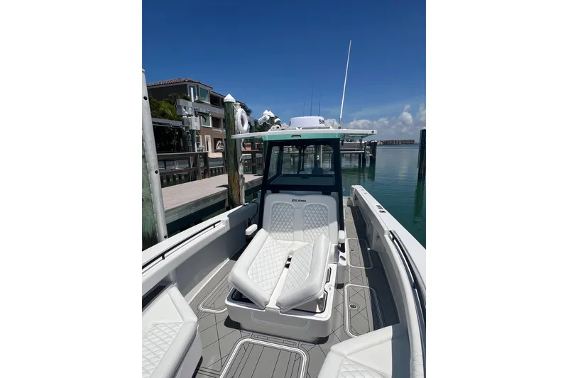 Slide: The Image of 2026 Reef Runner 340 boat docked, featuring sleek seating and modern design under clear blue skies. - 20