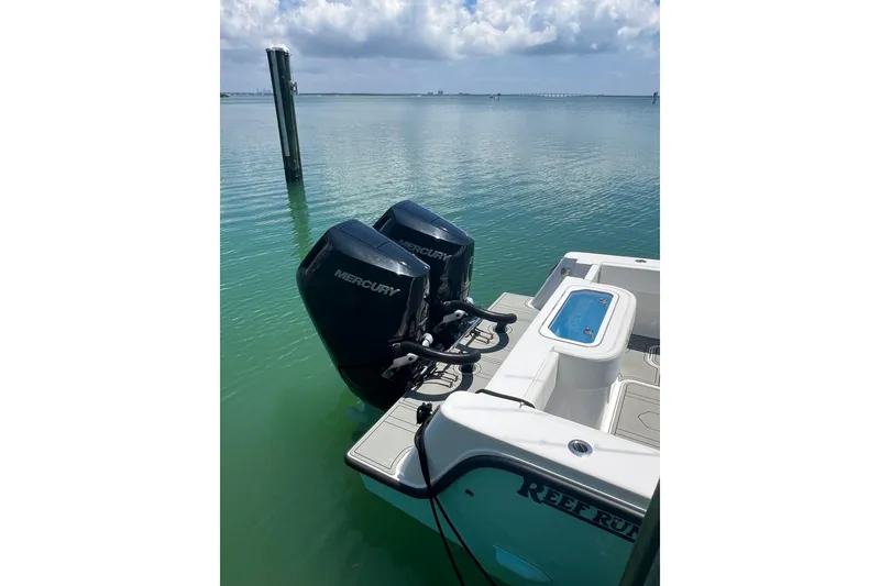 Slide: The Image of 2026 Reef Runner 340 boat with dual Mercury outboard engines on calm water. - 9