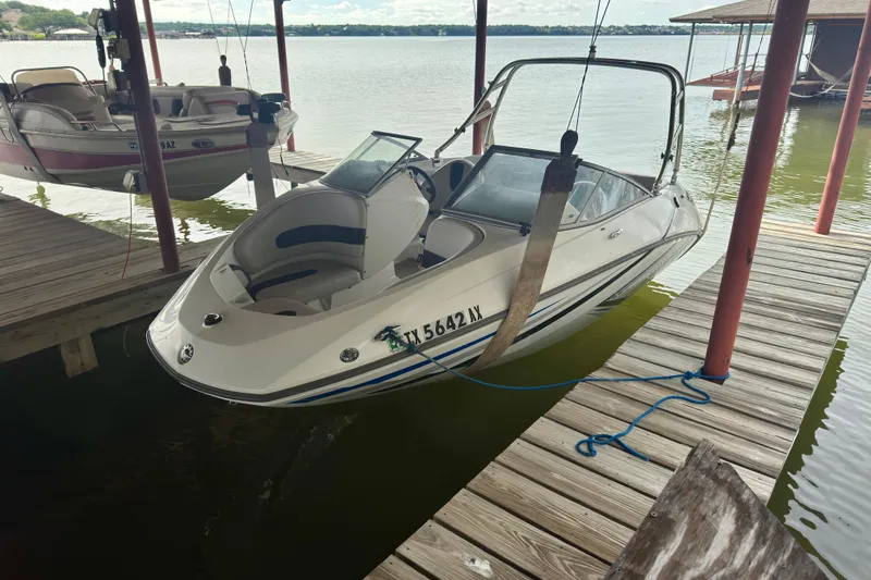 Slide: The Image of 2008 Sea-Doo 180 Challenger boat docked on a lake under a wooden canopy. - 2