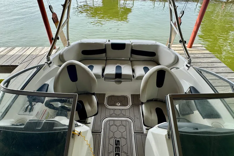 Slide: The Image of 2008 Sea-Doo 180 Challenger boat interior with seating and steering, docked by the water. - 5