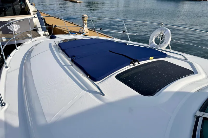 Slide: The Image of 2008 Sea Ray 44 Sundancer yacht deck with blue sunpad, docked by calm waters. - 45