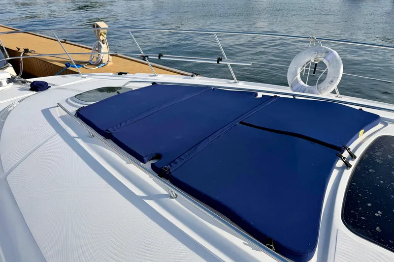 Slide: The Image of 2008 Sea Ray 44 Sundancer yacht with blue sunpad on deck, docked by water. - 46