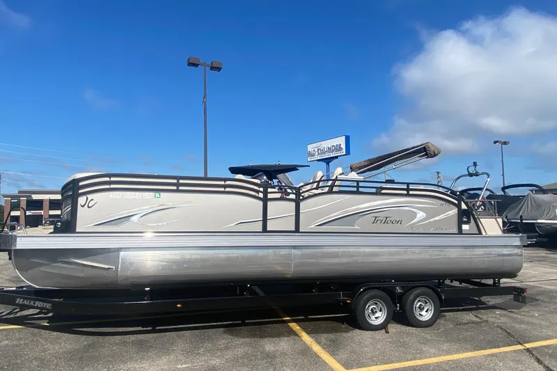 The Image of 2023 JC Swingback 27 TT Sport pontoon boat on trailer under clear blue sky. - 1