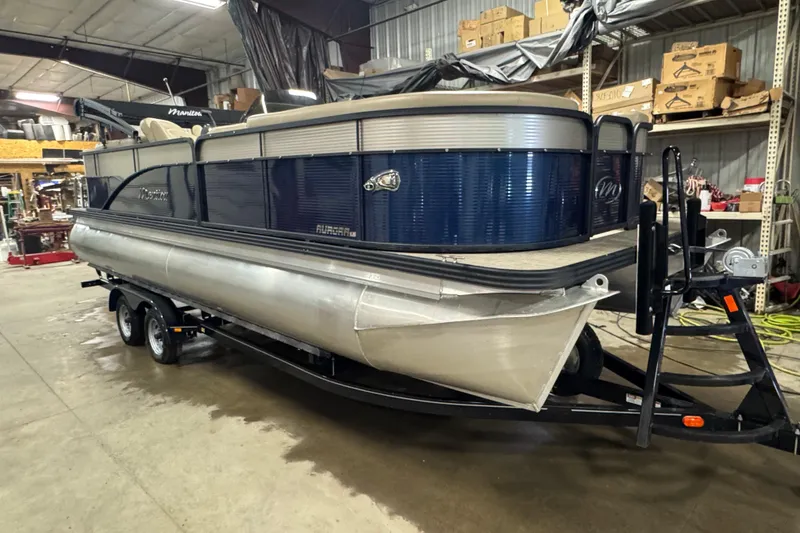 Slide: The Image of 2021 Manitou 22 Aurora LE Standard pontoon boat in a warehouse setting. - 2