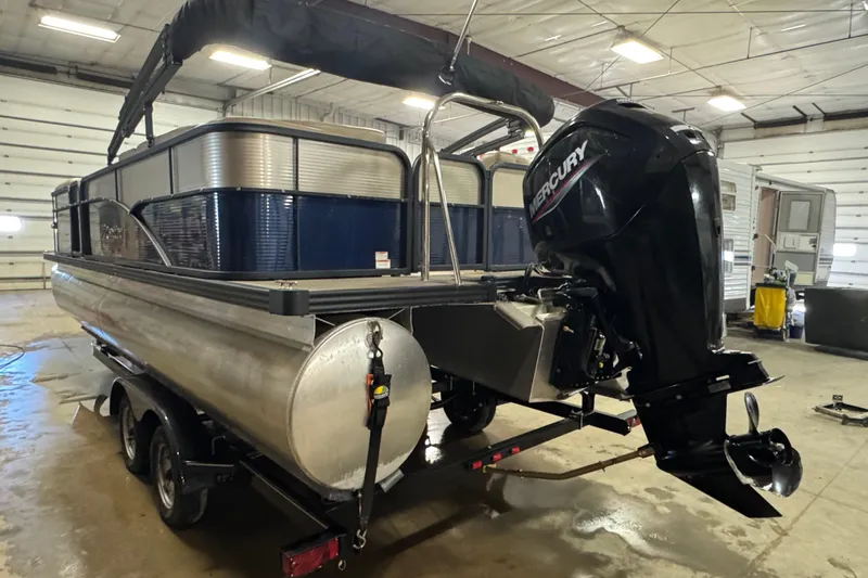Slide: The Image of 2021 Manitou 22 Aurora LE Standard pontoon boat with Mercury outboard motor in a garage. - 4